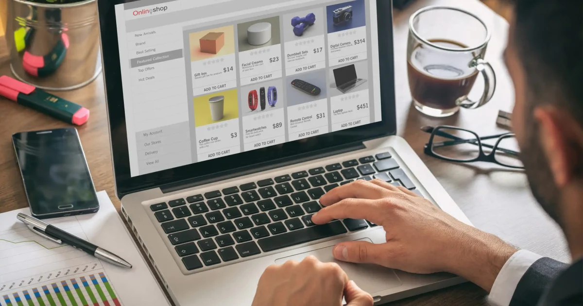 Online shop website developer, Man working with a computer laptop, eshop web page on the screen, office desk background.