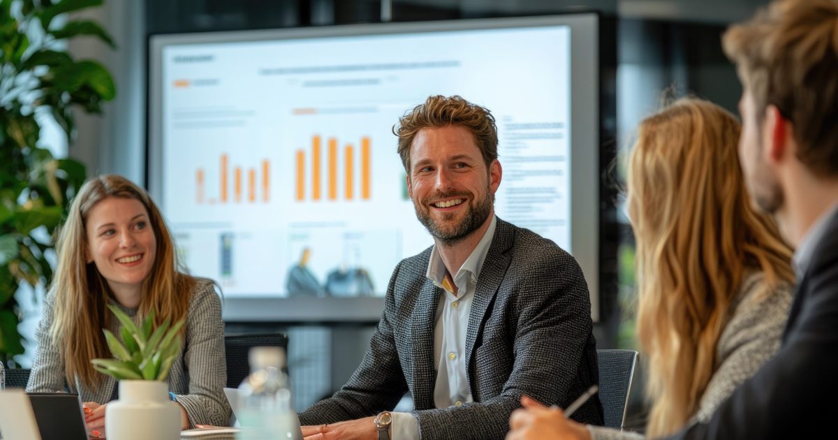 Diverse group of young professionals engaged in a productive business meeting with presentations and discussions in modern office setting.