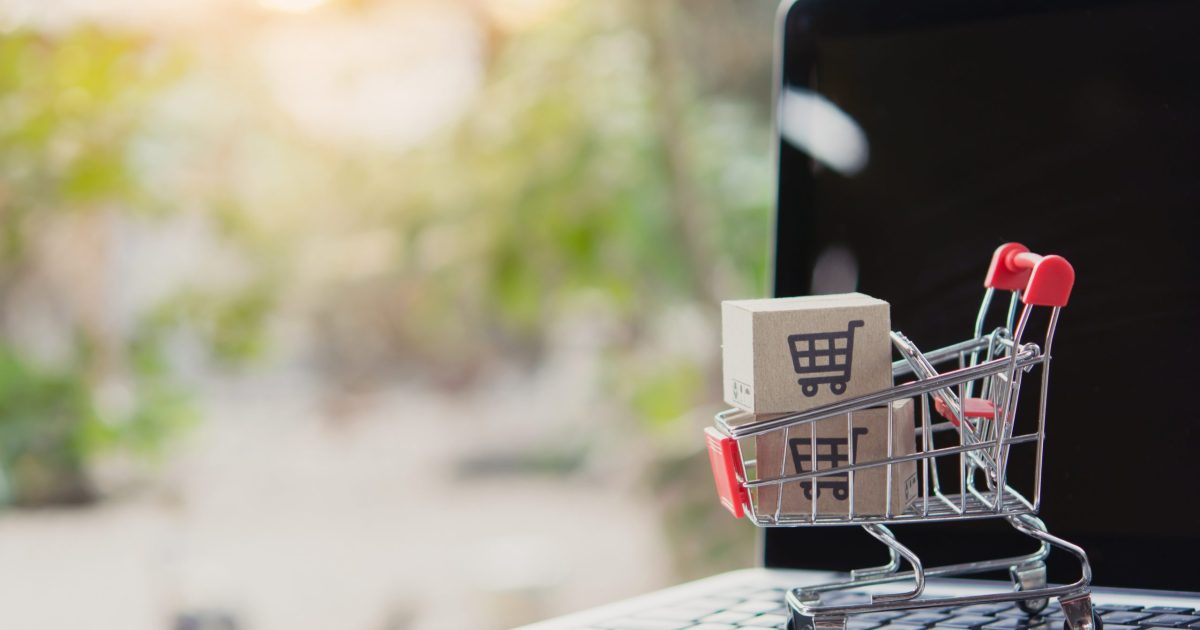 Shopping online. Cardboard box with a shopping cart logo in a trolley on laptop keyboard. Shopping service on The online web. offers home delivery