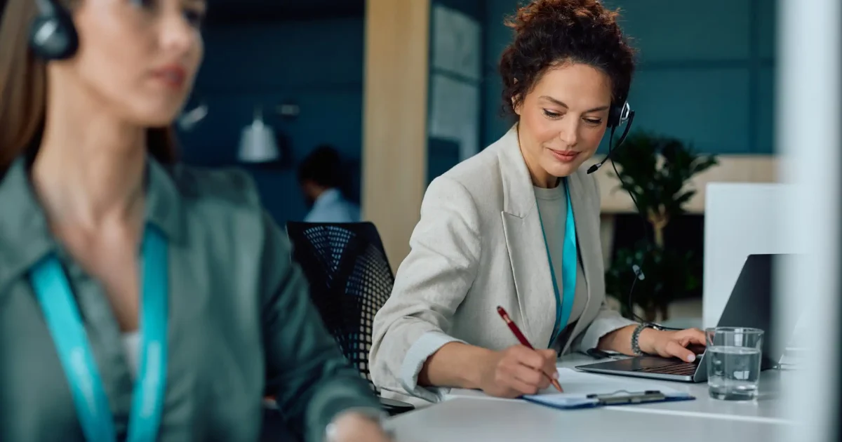 Smiling,Businesswoman,Using,Laptop,And,Taking,Notes,While,Working,In